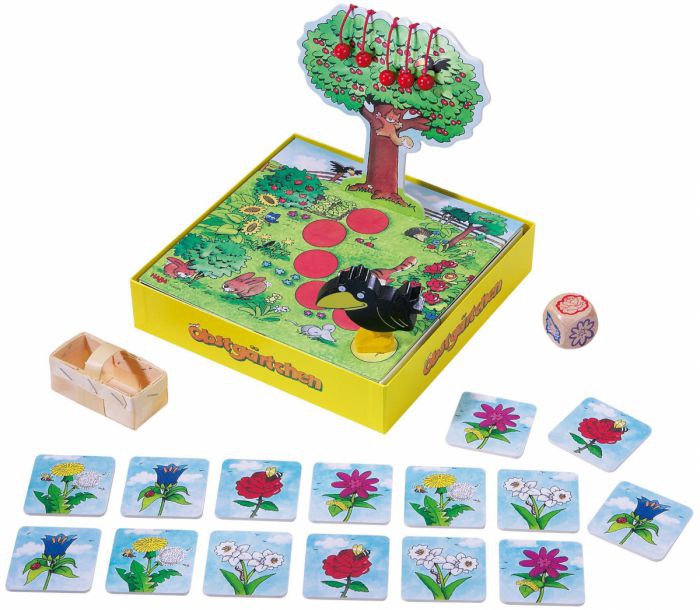 Auf einem Spielbrett steht eine Rabenfigur und ein Baum auf den Spielzeugkirschen gehängt sind. Vor dem Spielbrett liegen Memory-Karten, ein Würfel und ein Minitur-Obstkorb. 