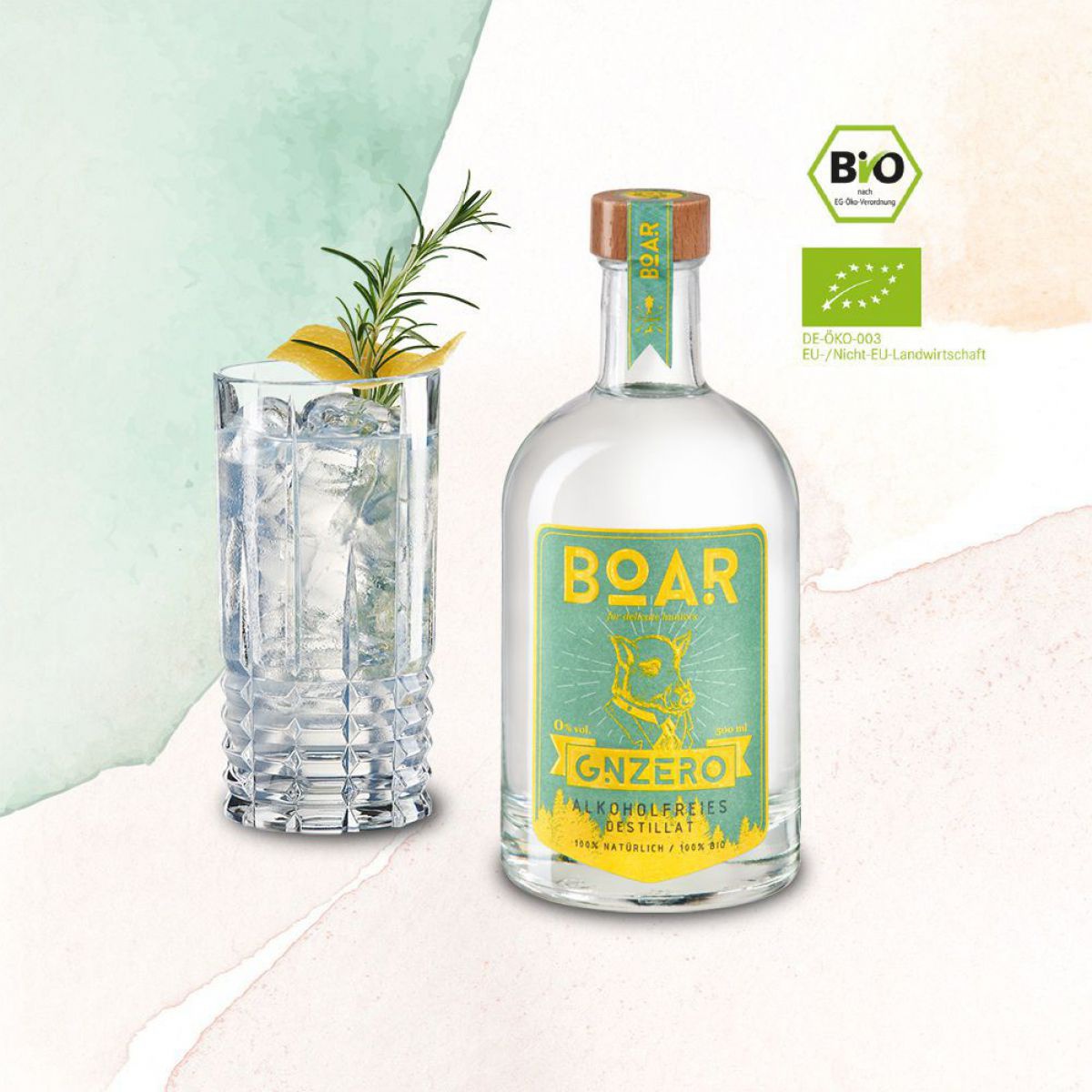Die Flasche des BOAR GNZERO ist in türkis und gelb gehalten, daneben ein gefülltes Glas mit Eis, Rosmarin und Zitronenzeste.