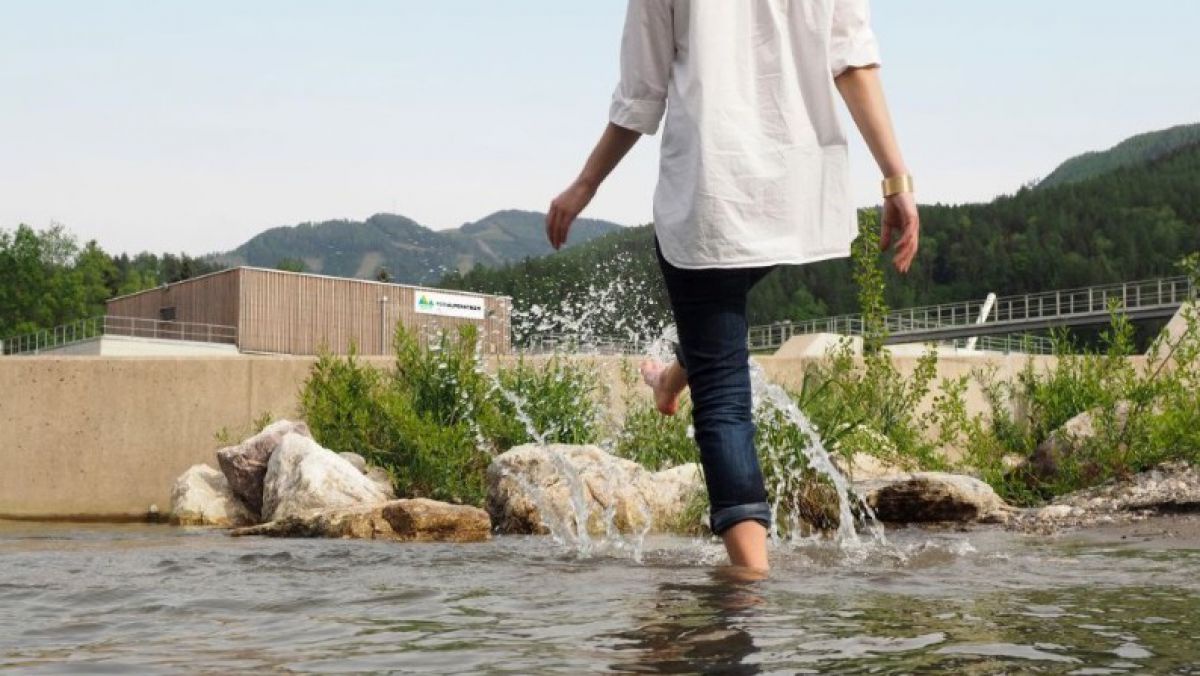 Mensch in aufgekrempelten Jeans steht in Fluss.