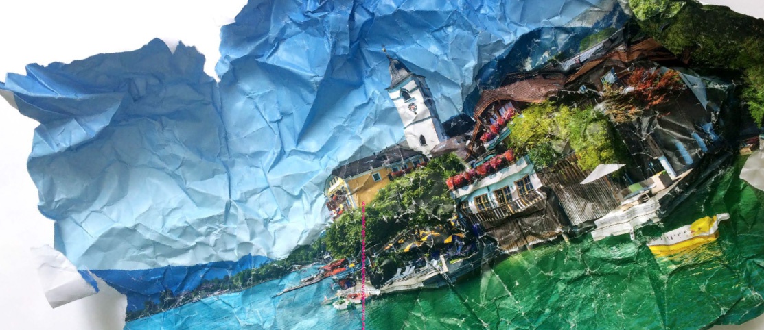 Auf einem zerknüllten Papier ist eine idyllische Stadtlandschaft am See mit blauem Himmel zu sehen.
