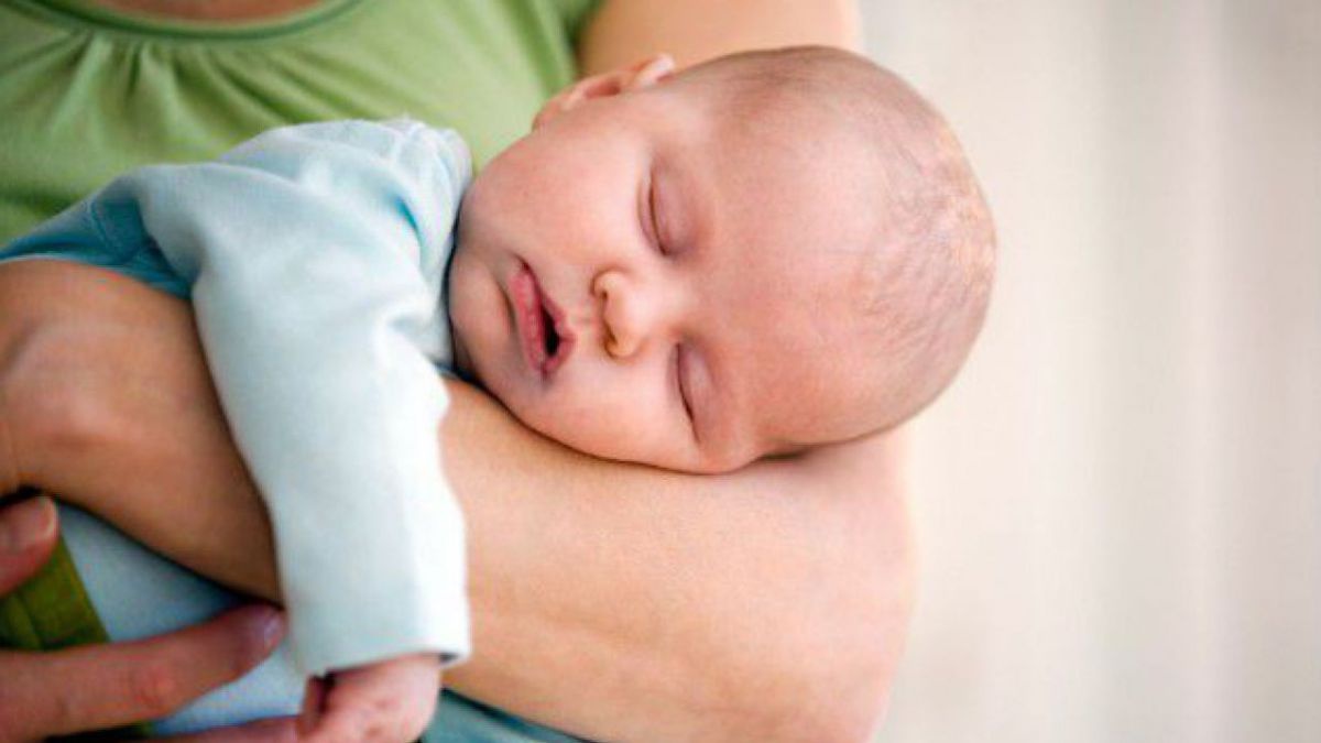 Baby schläft auf dem Arm der Mutter.