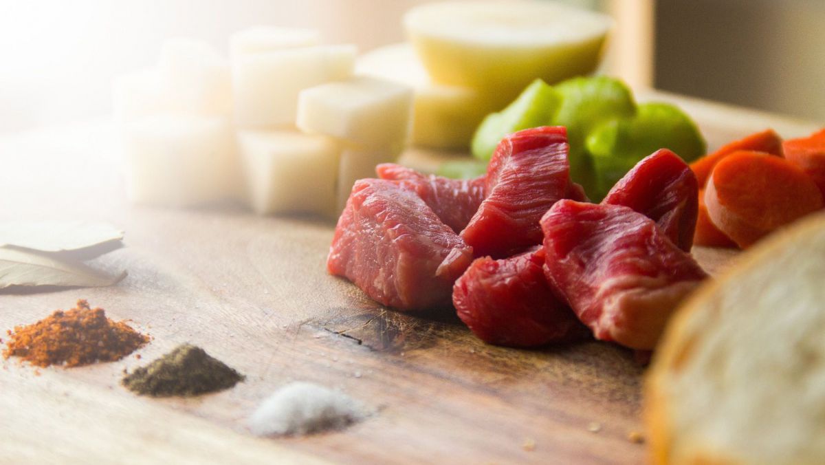 Fleisch- und Gemüsewürfel auf einem Brett.