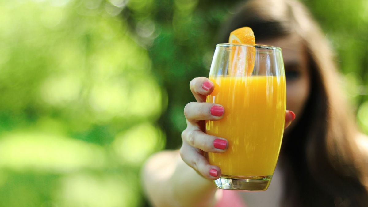 Frau hält Glas mit Orangensaft.
