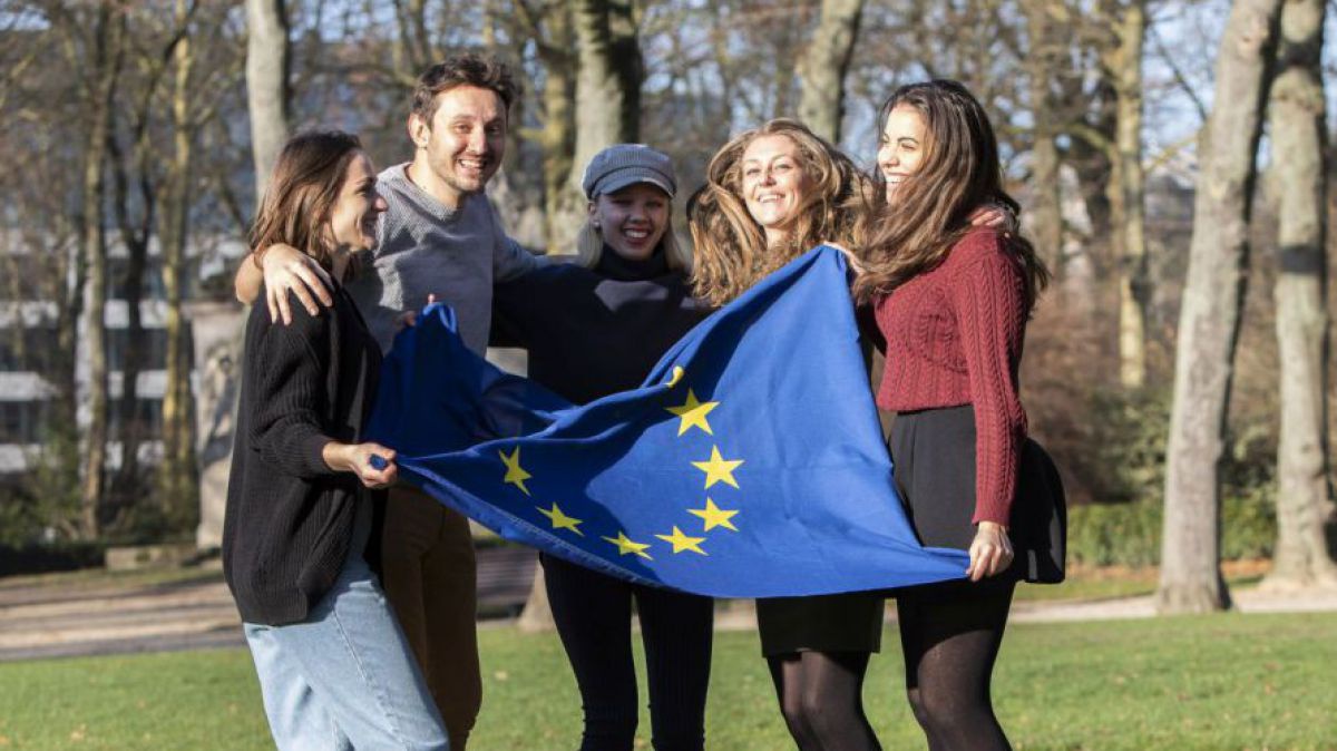 Junge Menschen halten gemeinsam eine EU-Flagge