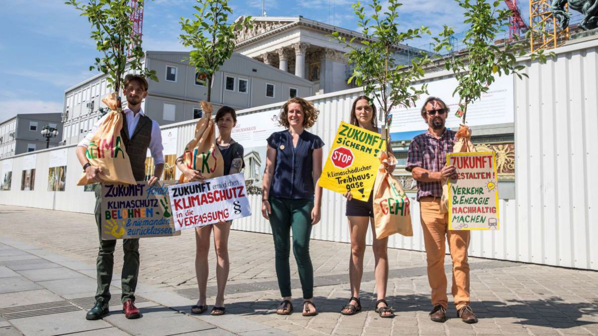 Junge Menschen halten Tafeln mit Klimaforderungen.