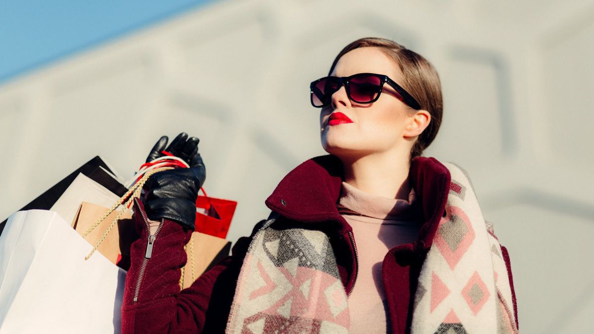 Geschminkte Frau mit Sonnenbrille und Einkaufstaschen. 