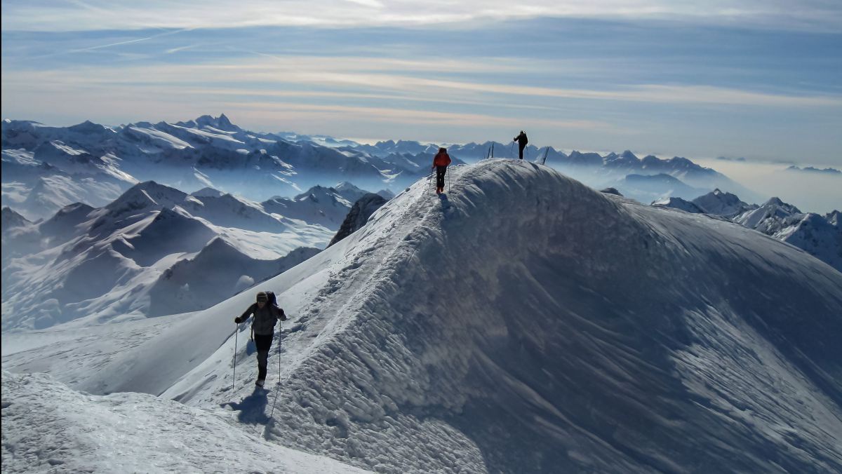 Drei Menschen auf Tourenschi am Berg.