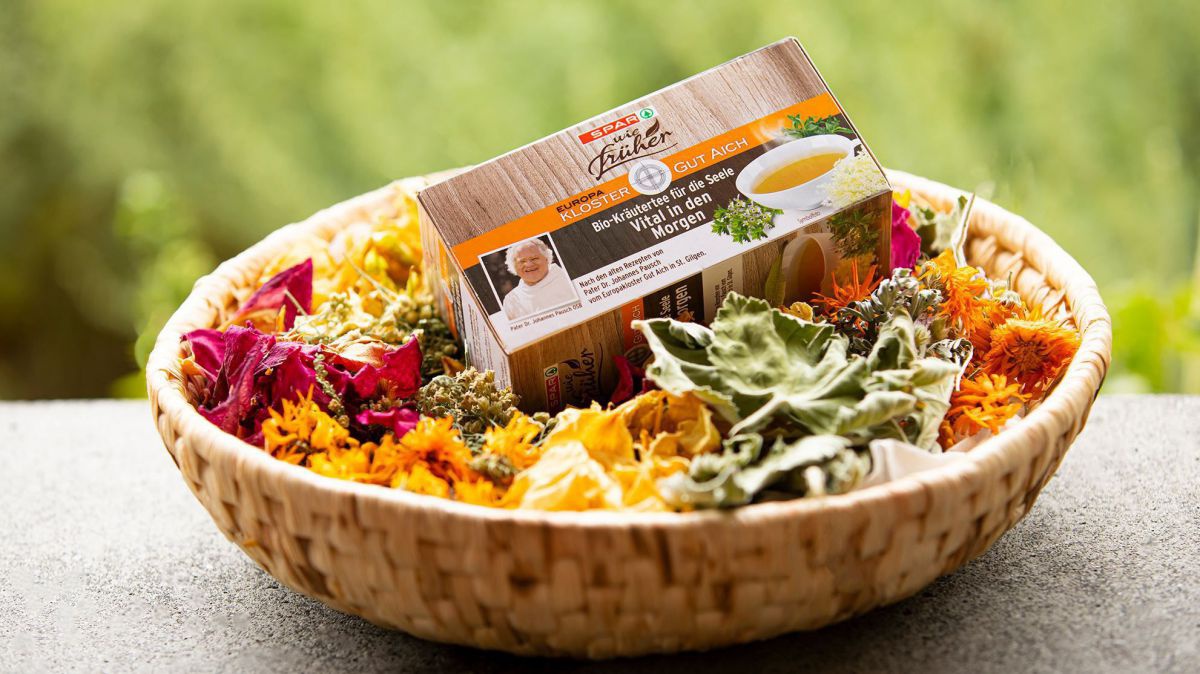 Korb mit Kräuterblüten und Teepackung.
