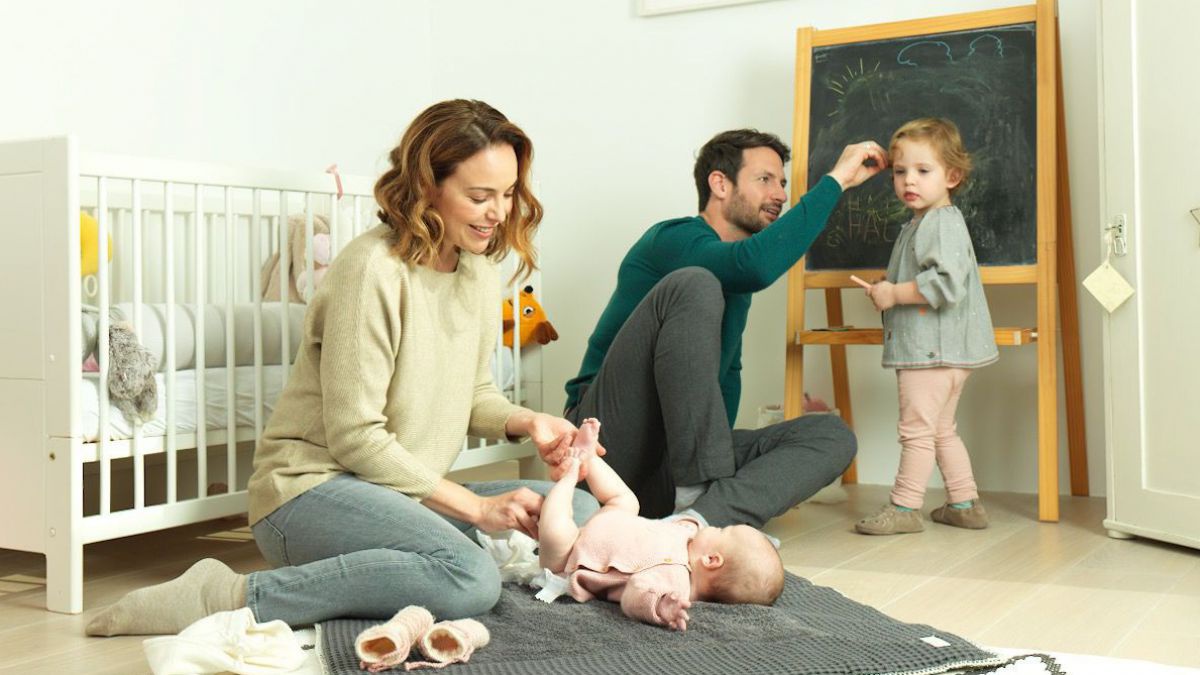 Familie mit kleinem Kind und Baby, das gewickelt wird.