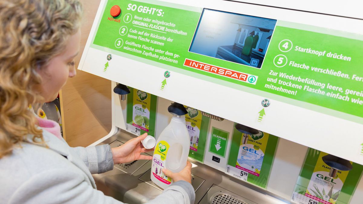 Frau füllt Plastikflasche an der Nachfüllstation mit Reinigungsmittel.