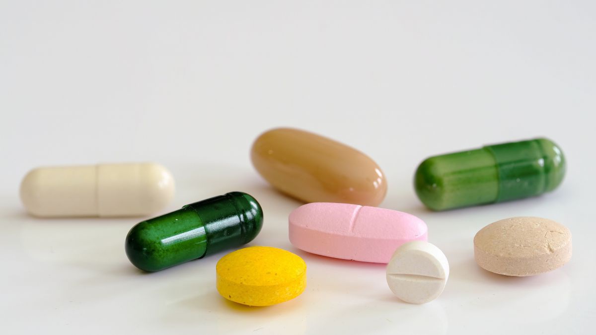 bunte Tabletten und Kapseln auf weißem Hintergrund.