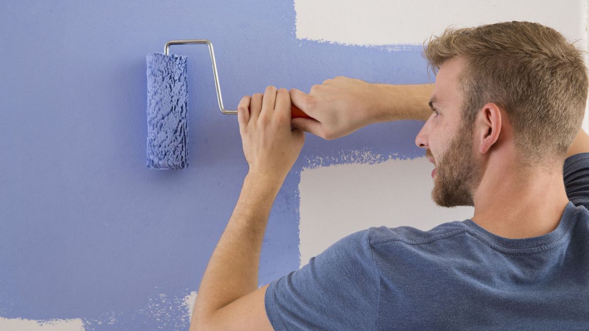 Mann streicht Wand.