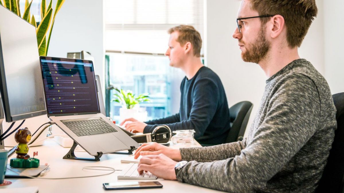 Zwei Männer sitzen vor dem Computer.