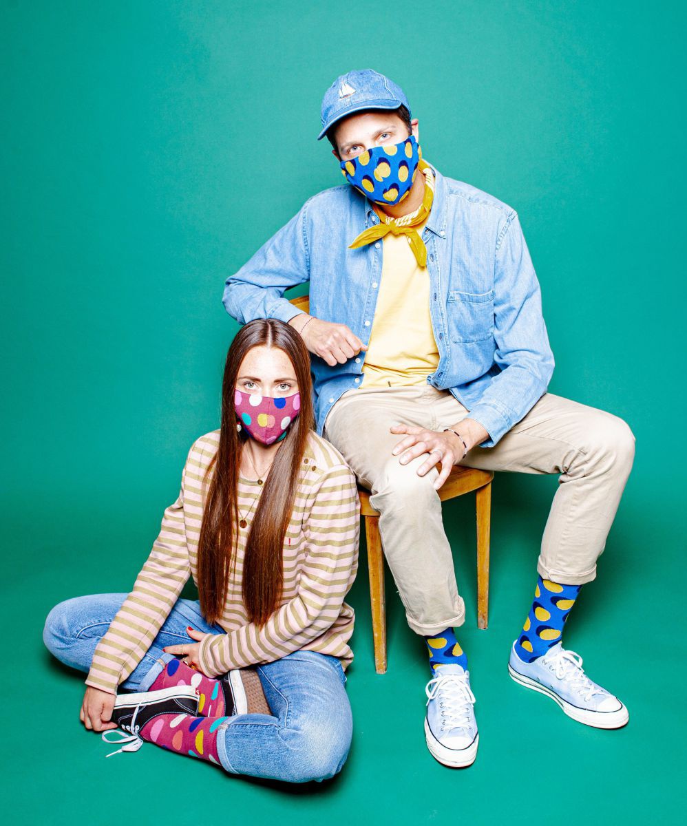 Eine Frau und ein Mann tragen Nasen-Mund-Schutzmasken passend zu ihren Socken. 