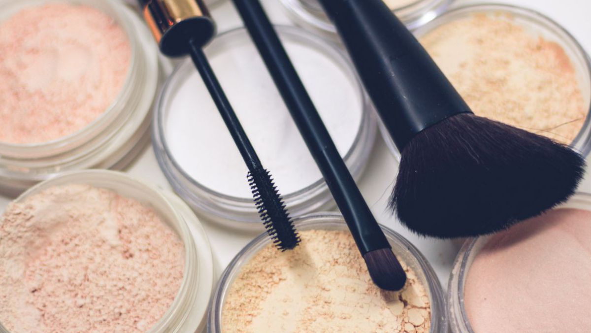 Hautfarbene Make-Up-Tigel auf denen Pinsel liegen.