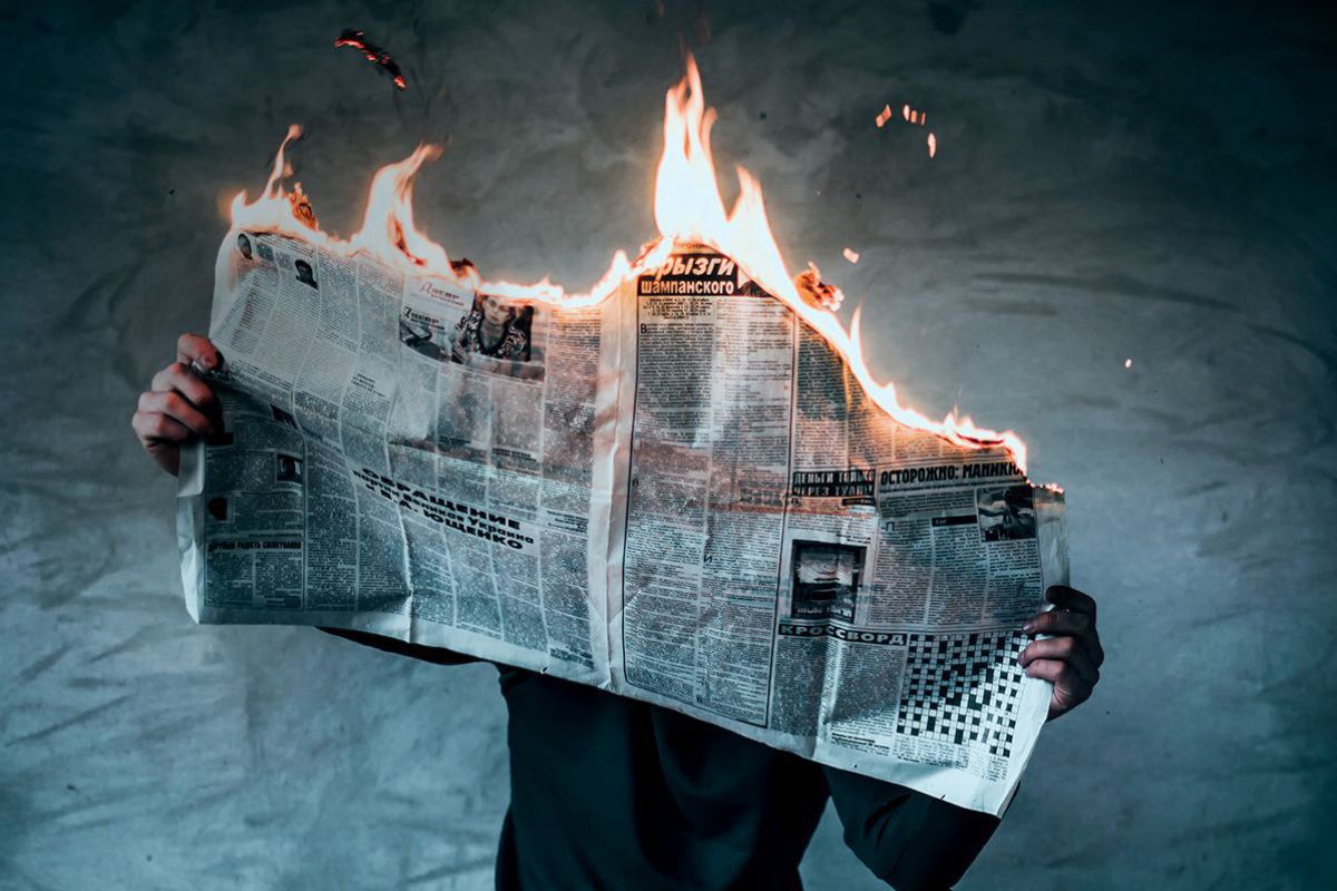 Eine Person hält eine aufgeschlagene, brennende Zeitschrift in Händen.