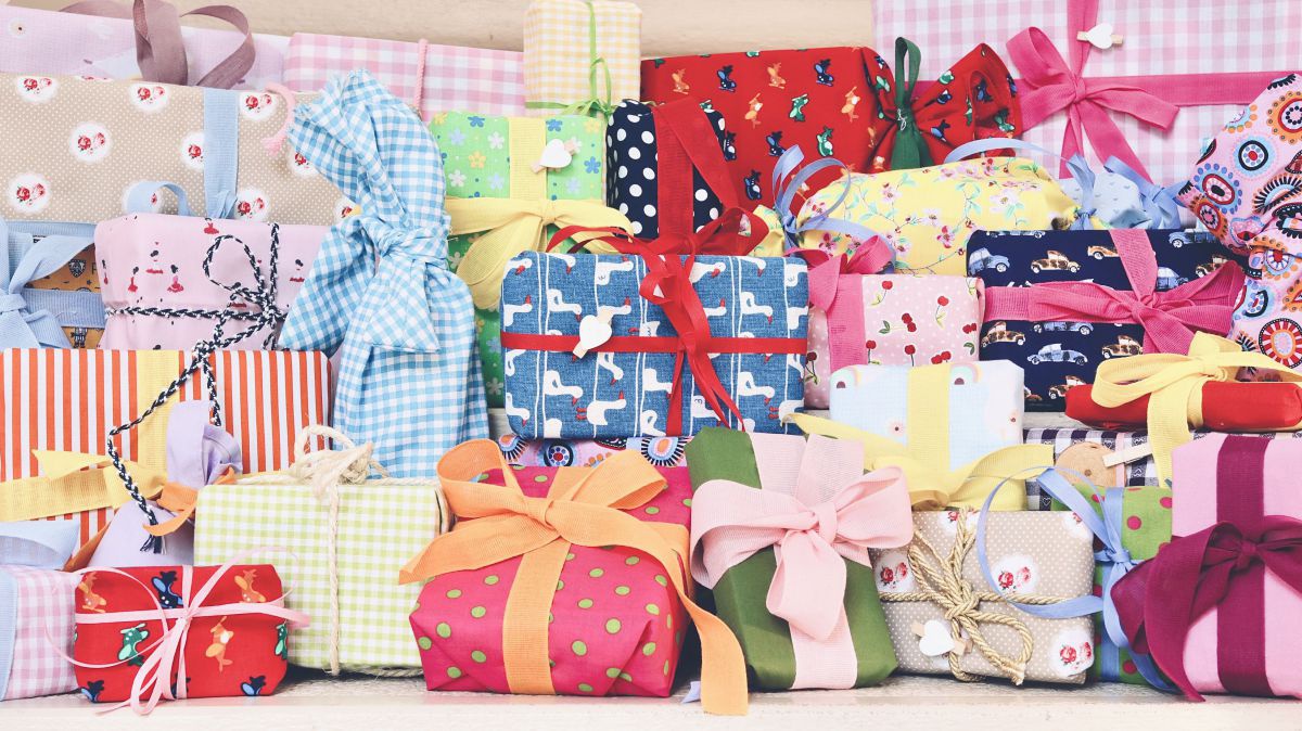Viele in bunten Geschenkstoff verpackte Pakete mit farbenfrohen Schleifen.