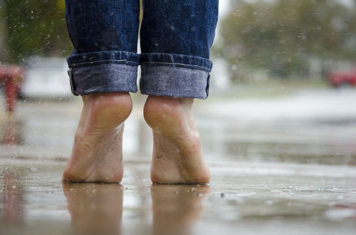 Eine Person steht barfuß im Regen auf den Zehenspitzen.