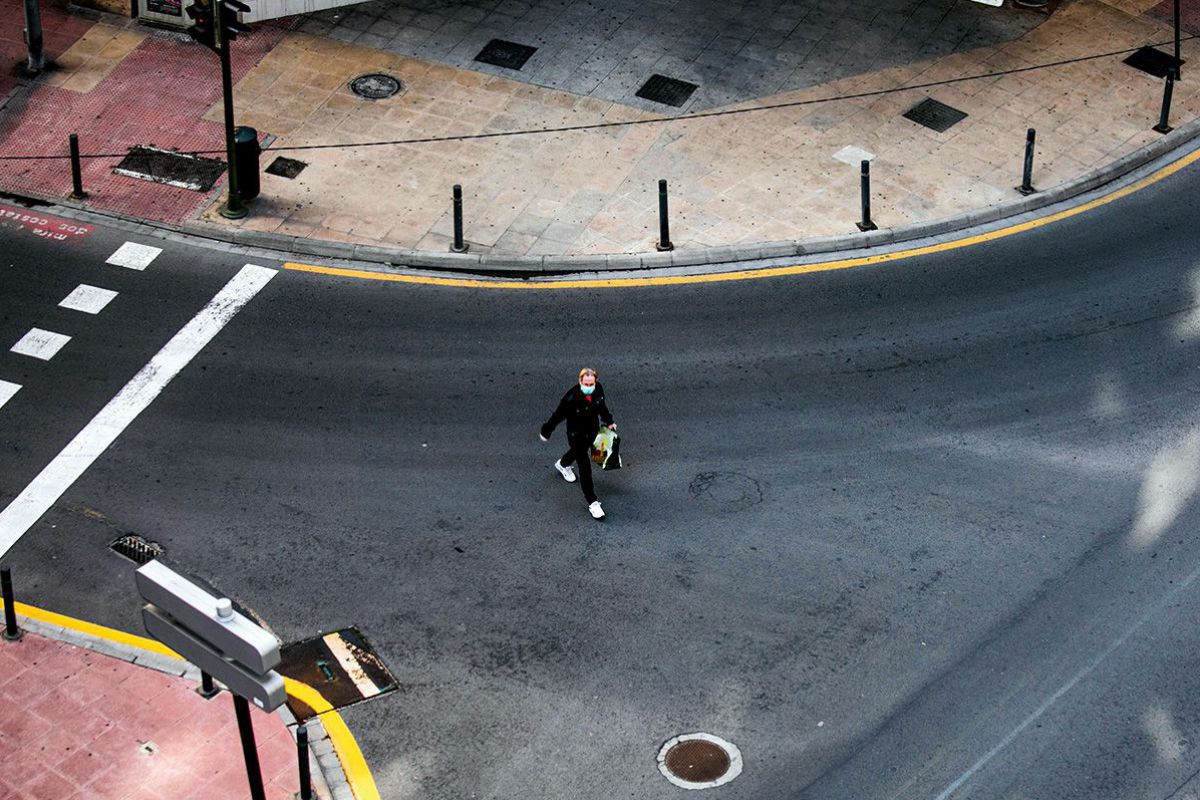 Ein Mann mit Nasen-Mundschutz geht allein mitten auf der Straße. Niemand anderer ist zu sehen.