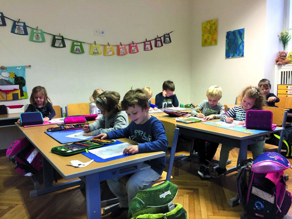 Kinder lernen und spielen fröhlich an Tischen.