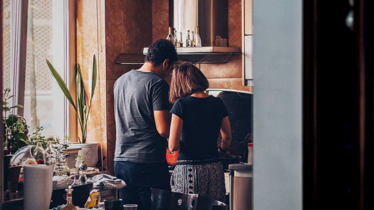 Zwei Personen kochen gemeinsam am Herd, man sieht sie von hinten. Der Raum macht einen gemütlichen Eindruck.