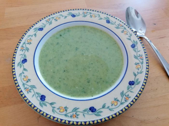 Eine grüne Cremesuppe in einem tiefen Teller mit Blumenmuster.