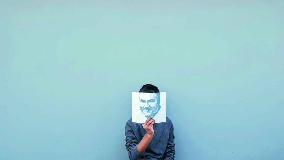 Eine Person hält vor einer hellblauen Wand ein Buch vors Gesicht. Auf dem Buchumschlag ist das Gesicht von Jürgen Schmücking so aufgezeichnet, als wäre er die Person, die das Buch hochhält.