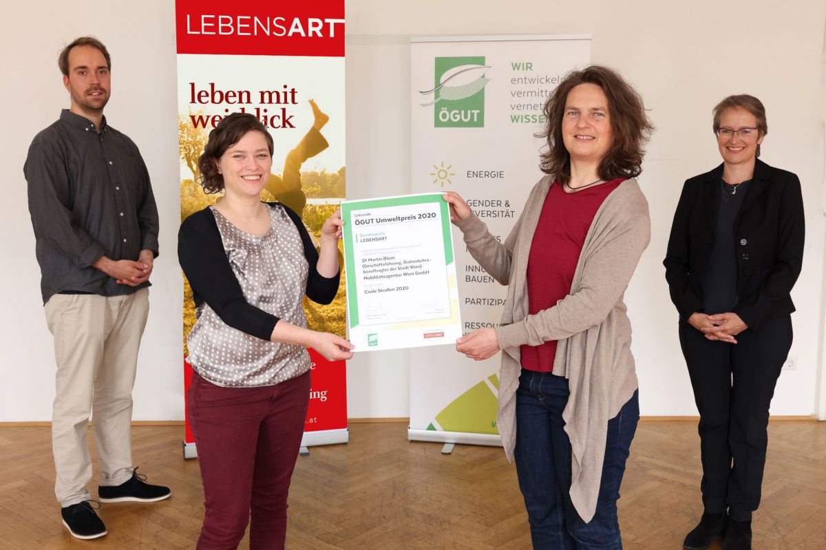 Zwei Frauen halten in der Mitte des Bildes die Urkunde hoch, flankiert von einem Mann und einer Frau. Dahinter stehen das Banner der LEBENSART und der ÖGUT.