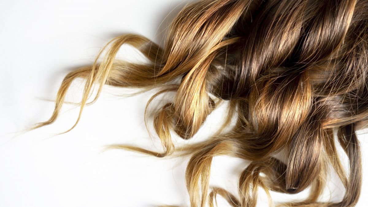 Gesund glänzende naturblonde Locken auf weißem Hintergrund.