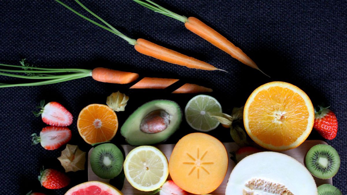 Aufgeschnittenes Obst und Gemüse auf einem dunkelblauen, strukturierten Tuch. 