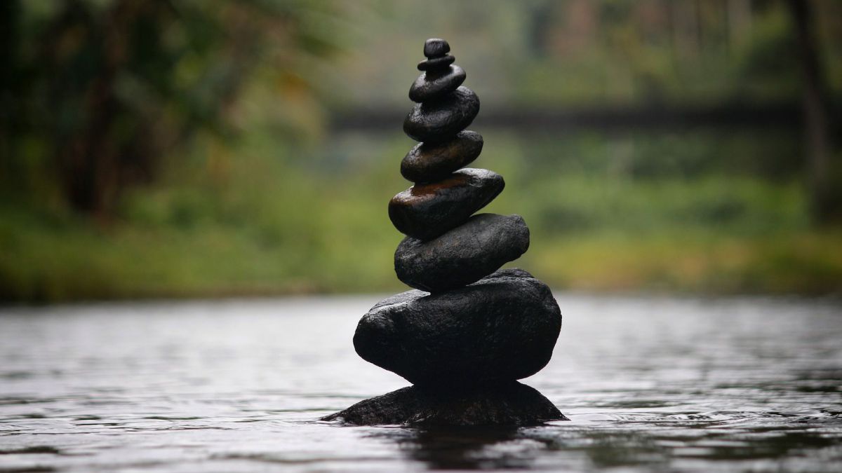 Steine sind an einem Fluss zu einem kleinen Turm gestapelt.