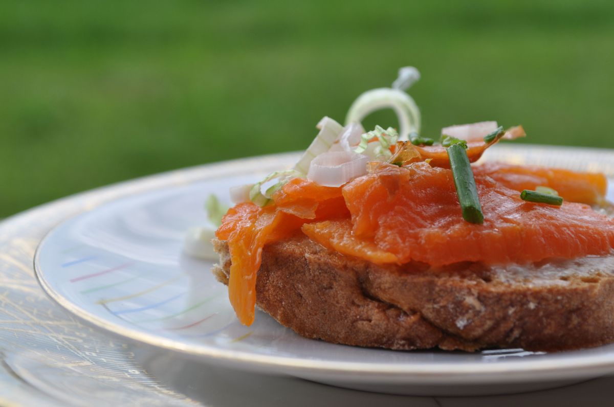 Ein mit Karottenlax belegtes Brot, mit Schnittlauch und Jungzwiebel ganiert.