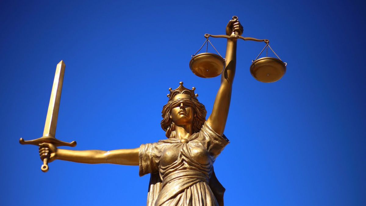 Eine goldene Statue mit verbundenen Augen, Waage in der einen, Schwert in der anderen Hand.