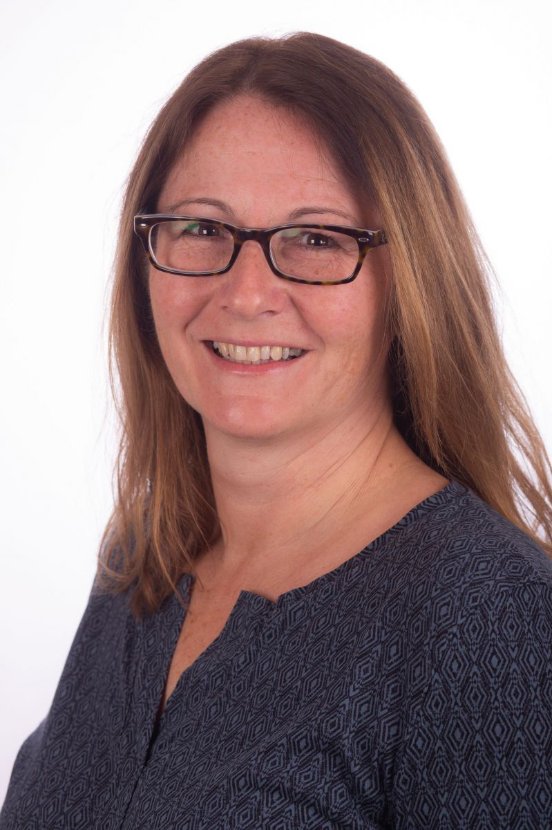 Ein Portraitfoto von Martina Schmidthaler. Sie trägt eine Brille und hat lange Haare. Sie lächelt vor weißem Hintergrund in die Kamera.