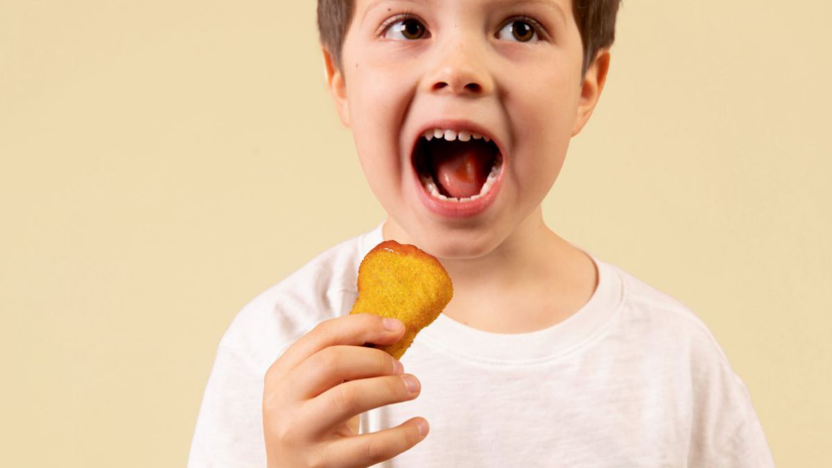 Ein Bub isst ein Chicken Nugget