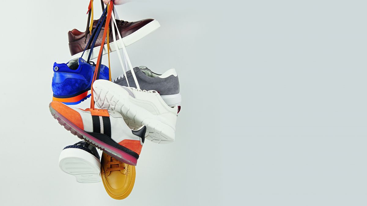 Eine Hand hält verschiedene Paar Schuhe an den Schnürsenkeln hoch.