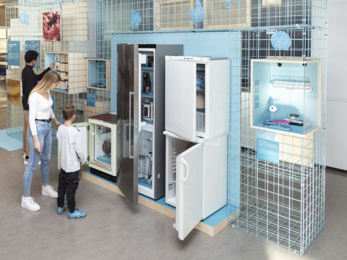 Im Ausstellungsraum ist eine hellblaue Gitterwand aufgebaut. Eingepasst sind Exponate zum Thema Haltbarmachung wie beispielsweise Kühlgeräte.