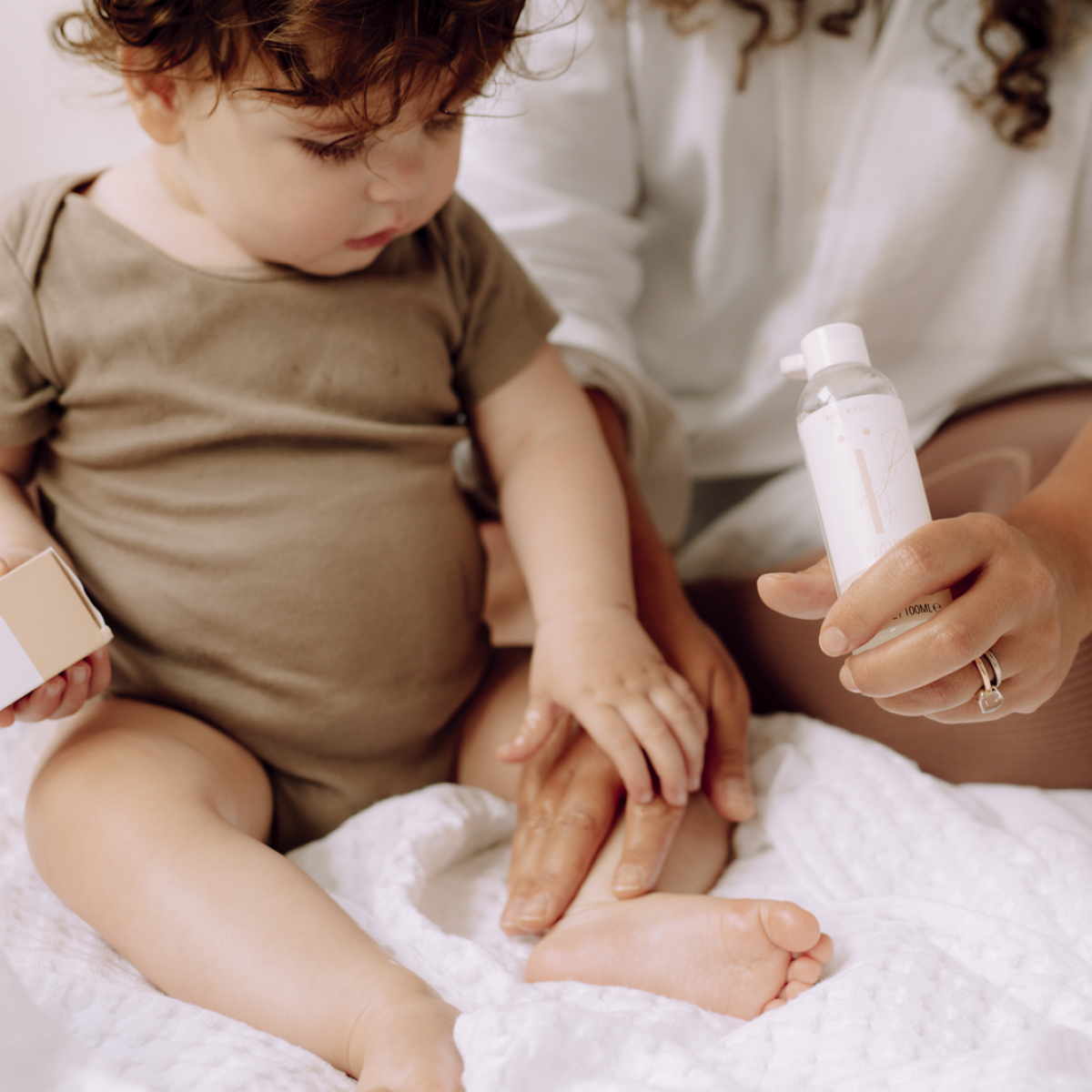 Die Beine eines Babys werden mit Öl eingerieben.