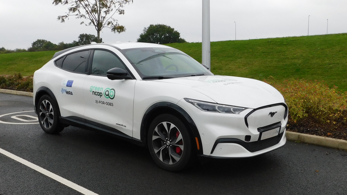 Ein weißes E-Auto in sehr modernem Design untwegs auf einer regenfeuchten Straße.