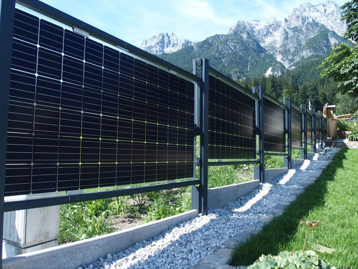 Ein Gartenzaun in optisch gängiger Konstruktion, jedoch bestehen die Zaunflächen aus Panelen mit Solarzellen.
