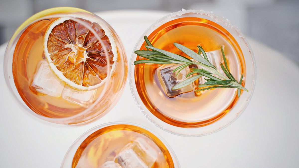Drei Cocktails mit bernsteinfarbener, klarer Flüssigkeit von oben fotografiert.