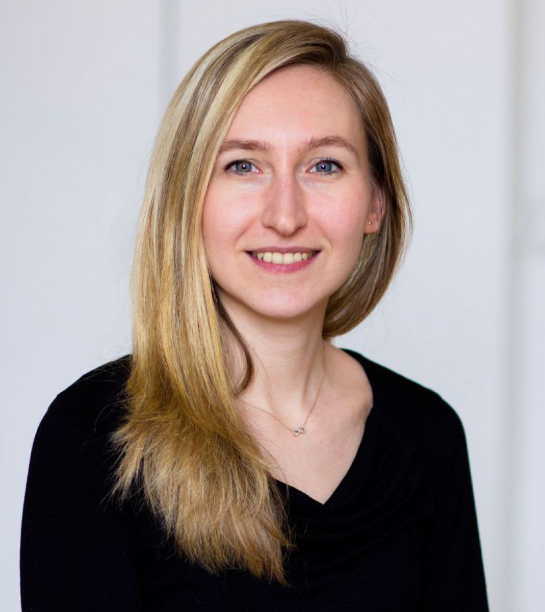 Eine junge Frau mit langen, blonden Haaren, hellen Augen und einer schmalen Nase. Sie blickt direkt in die Kamera und lächelt.