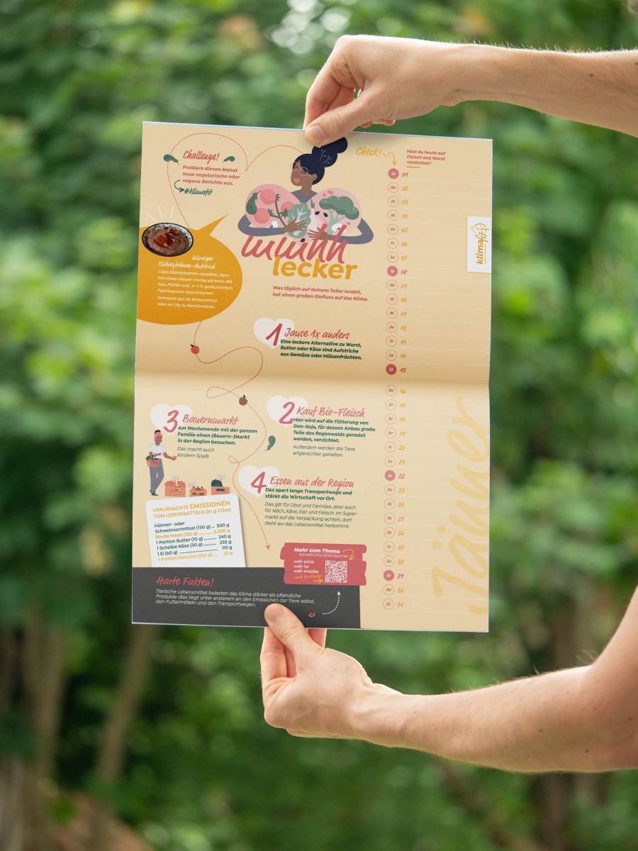 Zwei Hände halten den Klimafit-Wandkalender und zeigen die Tipps für diesen Monat.