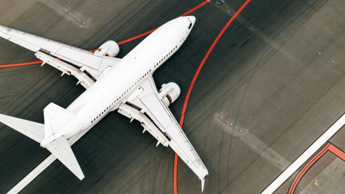 Blick aus der Vogelperspektive auf ein Passagierflugzeug auf der Start- oder Landebahn eines Flughafens.
