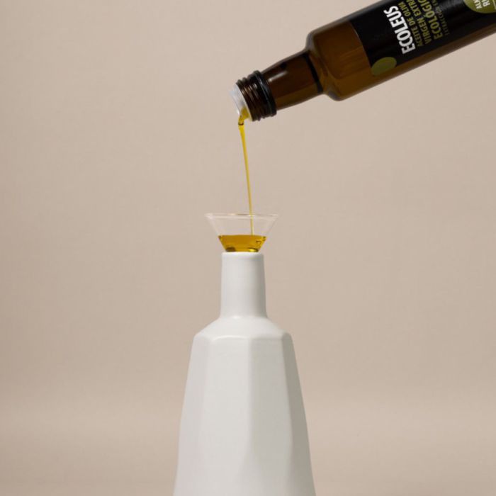Olivenöl wird aus einer Glasflasche in einen Tonflakon gegossen