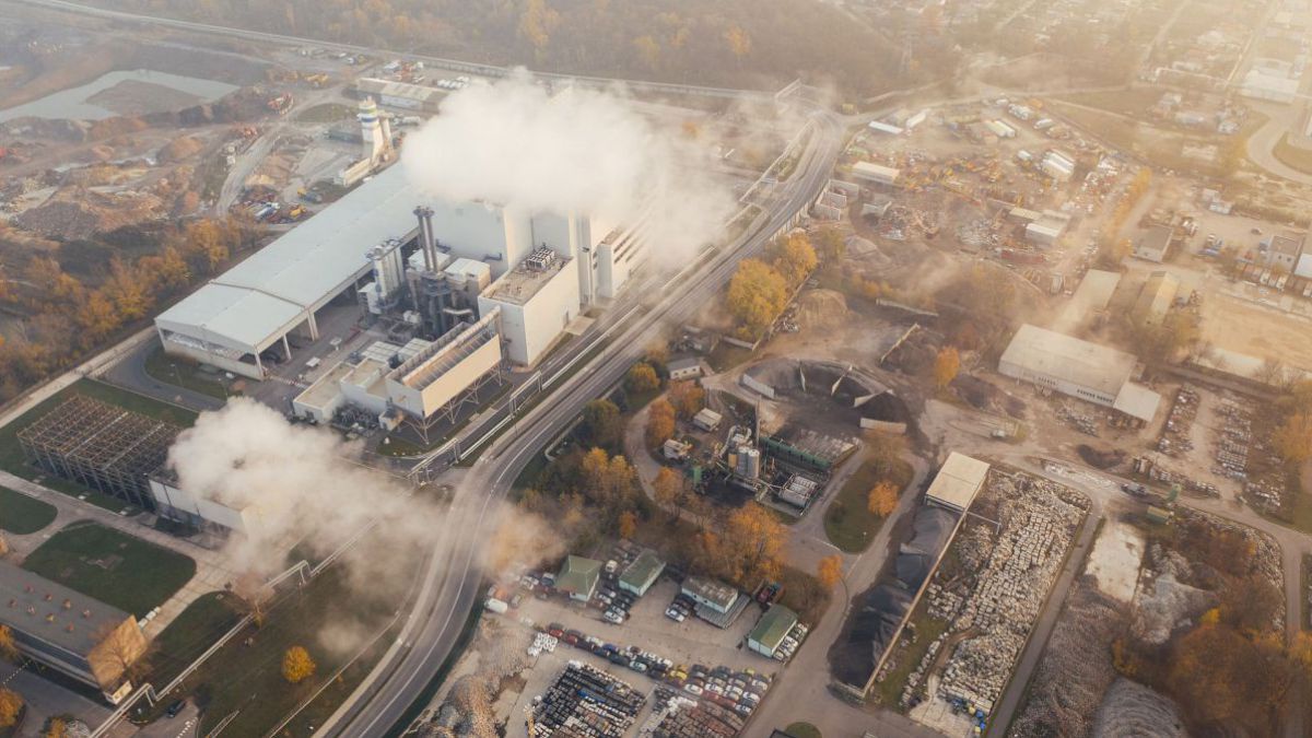 Eine Luftansicht eines Industriegebietes einer Stadt. In der Luft hängen Nebelfetzen.