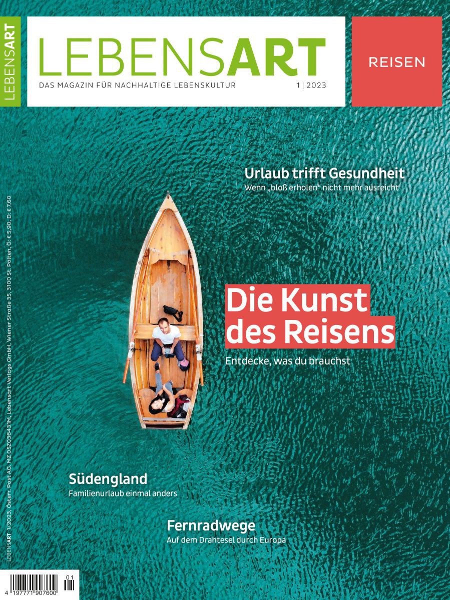 Ein Holzboot aus der Vogelperspektive auf türkisgrünem Wasser. Das Paar darin blickt hinauf zur Kamera. Daneben steht 