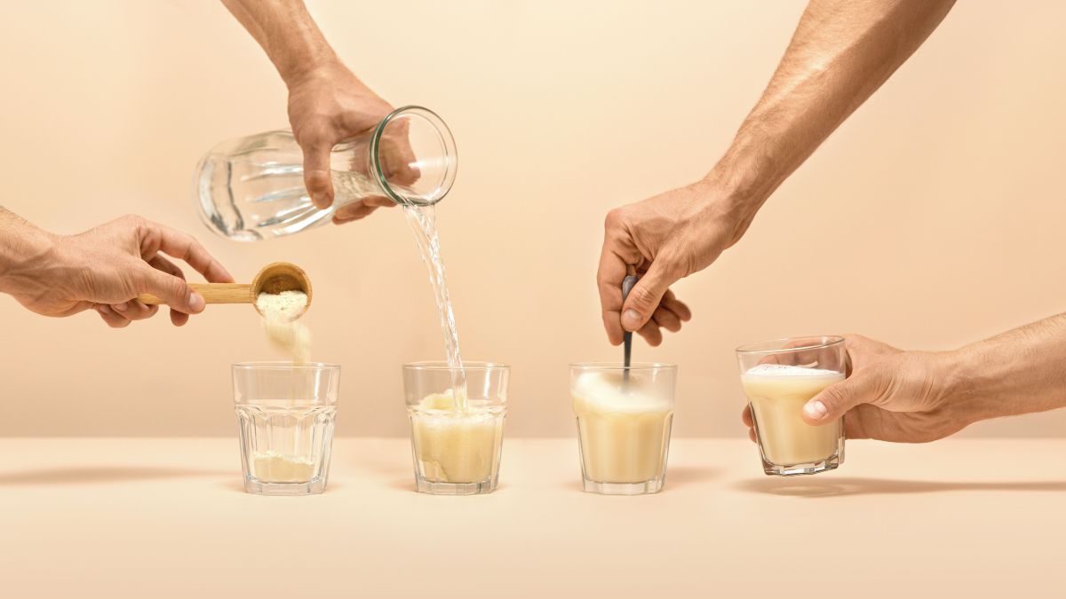 Vier Gläser nebeneinander zeigen die Anrührschritte des Haferdrinks: zuerst Pulver, dann Wasser ins Glas geben, mit einem Löffel verrühren und fertig.