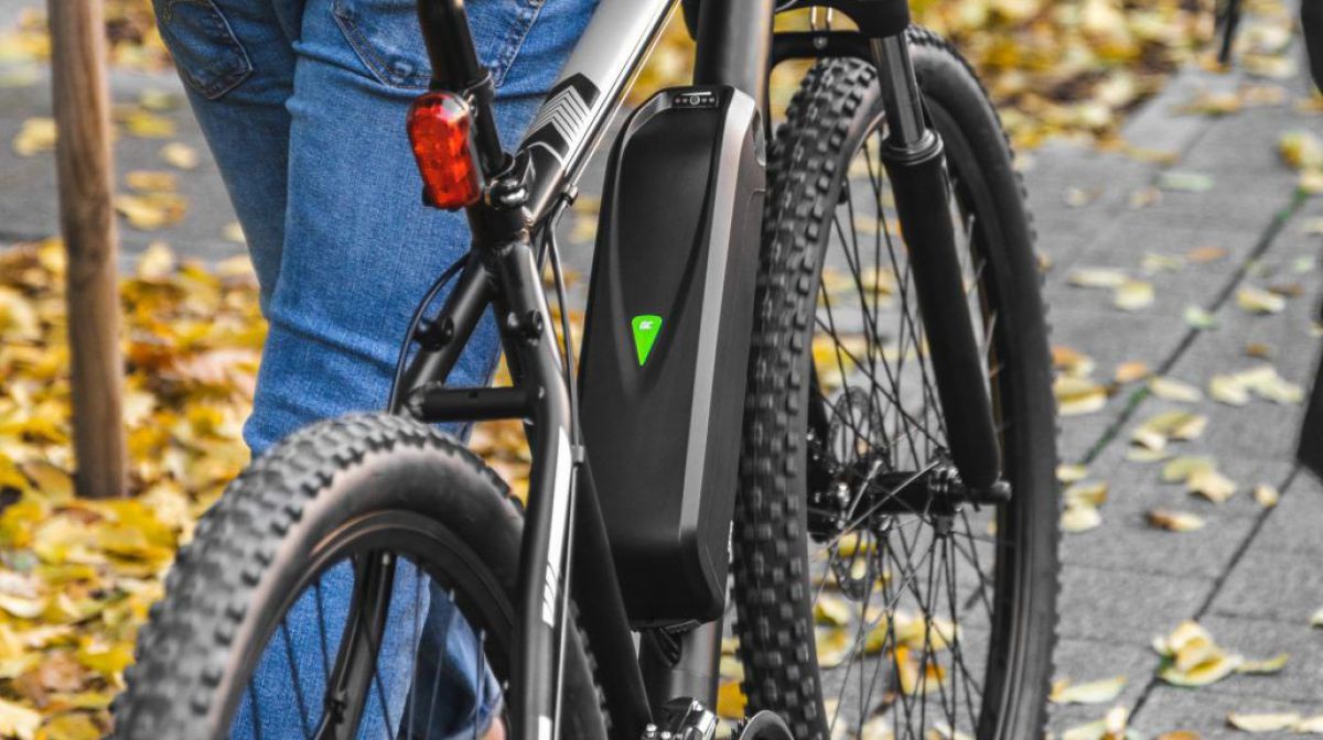Ein Foto eines E-Bikes, das gerade von jemanden über eine herbstliche Straße geschoben wird.