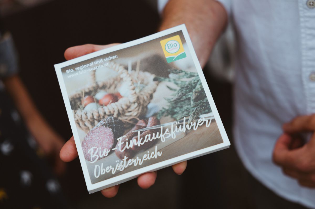 Man sieht den Bioeinkaufsführer in einem handlichen, quadratischen Format (ca. 10x10 cm). Am Cover sind Wurst, Eier und grüner Spargel zu sehen.